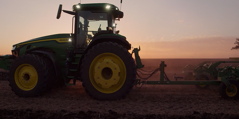 John Deere's autonomous tractor driving across a field with no driver in the seat.