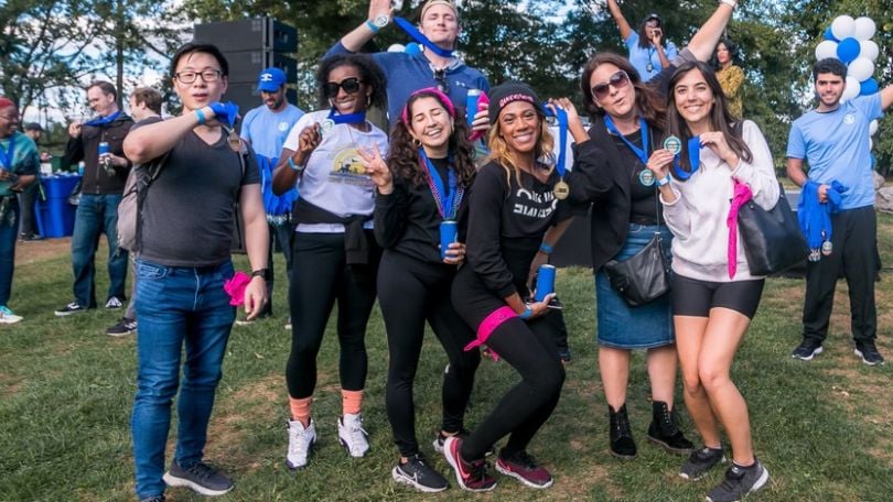 Justworks employees pose for a group photo while holding medals and wearing activewear at an outdoor event.