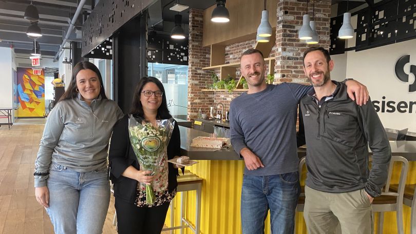 Four employees gather for a group picture at the kitchen counter of Sisense’s NYC office.