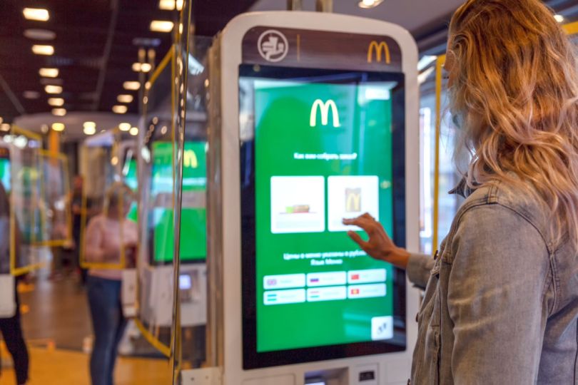 A customer orders a meal on a touch screen menu. 