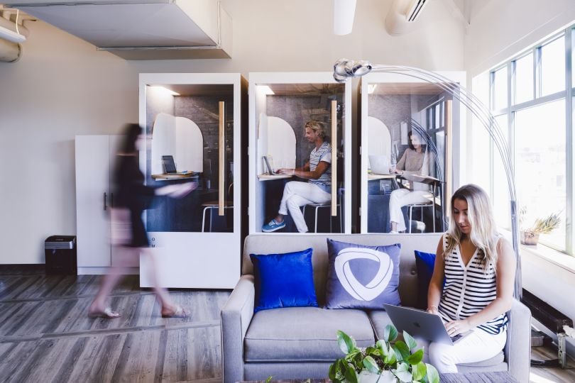 Mirakl team members in individual working “booths” in their office, with nearby lounge seating area. 