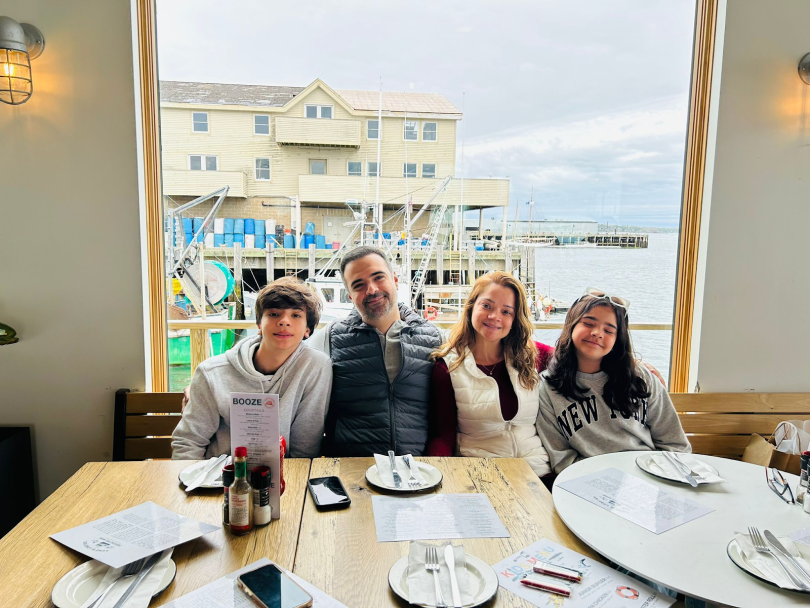 Felipe Dias Morais Magalhães, his wife and their two children pose for a photo at a restaurant in New England. 