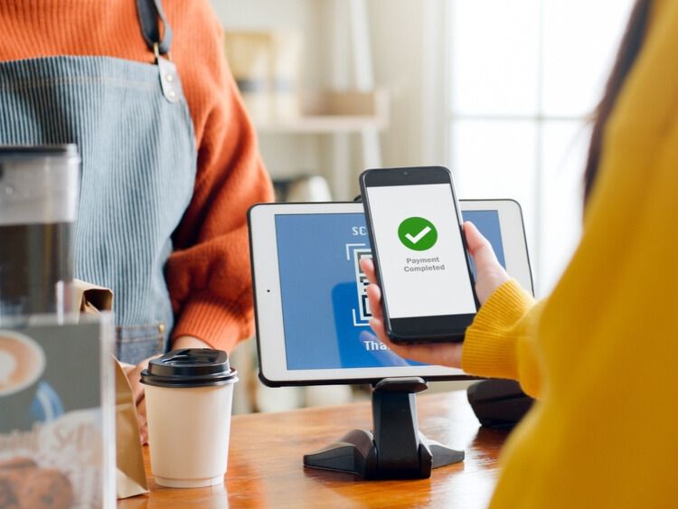 Woman using point-of-sale system to make purchase at coffee shop