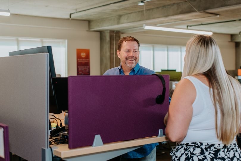 Pie Insurance President and Co-Founder Dax Craig stands at a desk talking to a colleague.