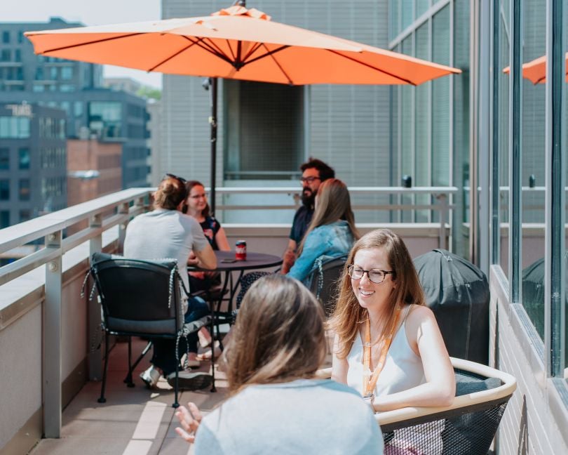 Pie employees sit on a balcony on a sunny day, chatting.