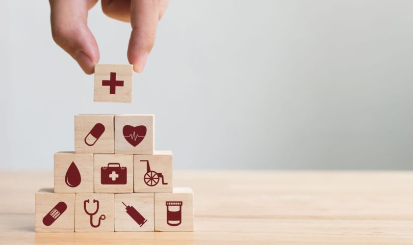 A pyramid of wooden blocks with icons related to health care.