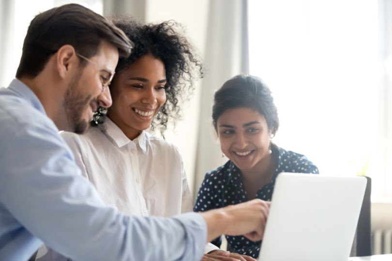 Happy business colleagues looking at a laptop together, smiling.