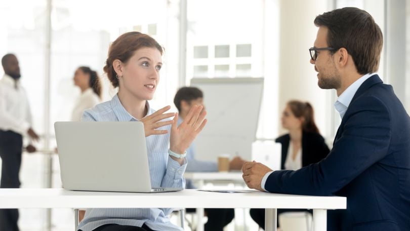 Two co-workers in discussion with hand gestures