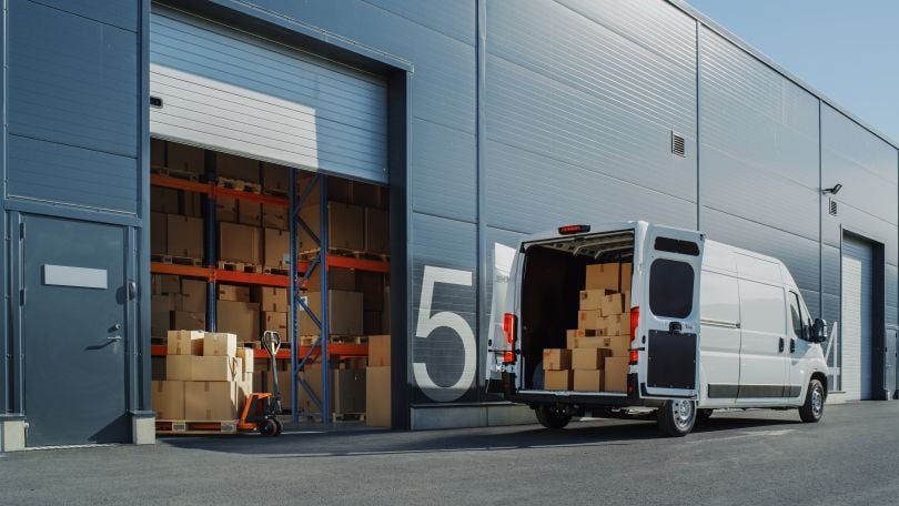 A delivery truck sits at a dock while being loaded