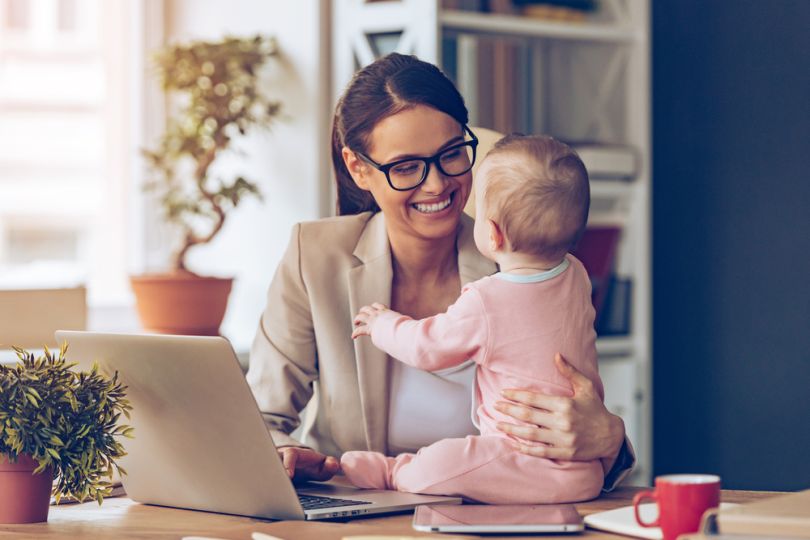 Working mom with baby on desk, smiling