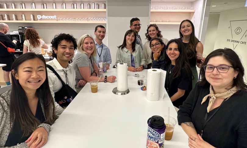 Eleven dscout team members gather around a table in the office kitchen, smiling for the photo.