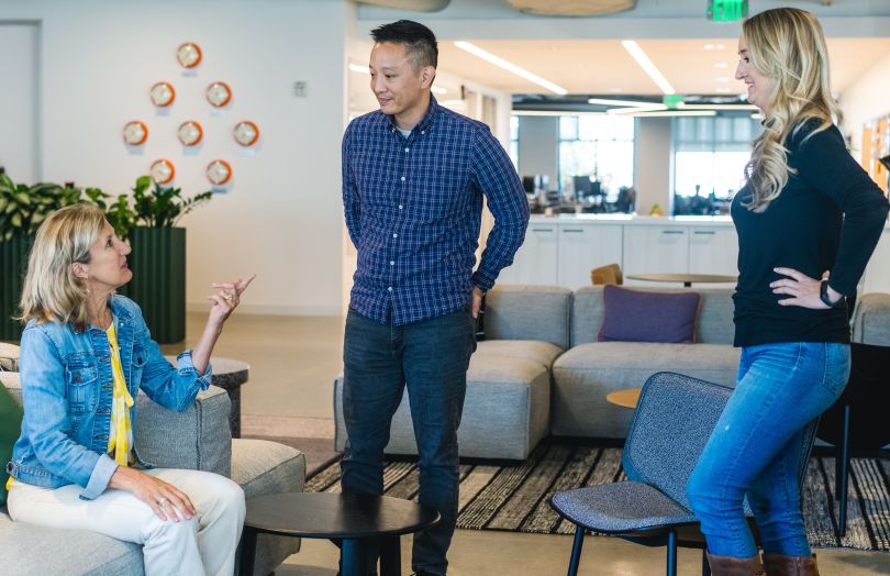 Three Udemy employees socializing in an office gathering area.