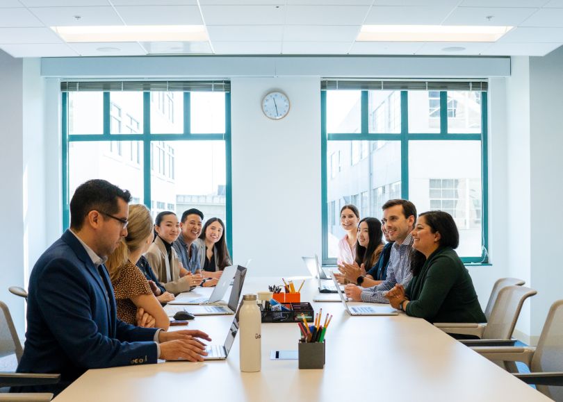 Udemy team meeting at a long conference table.