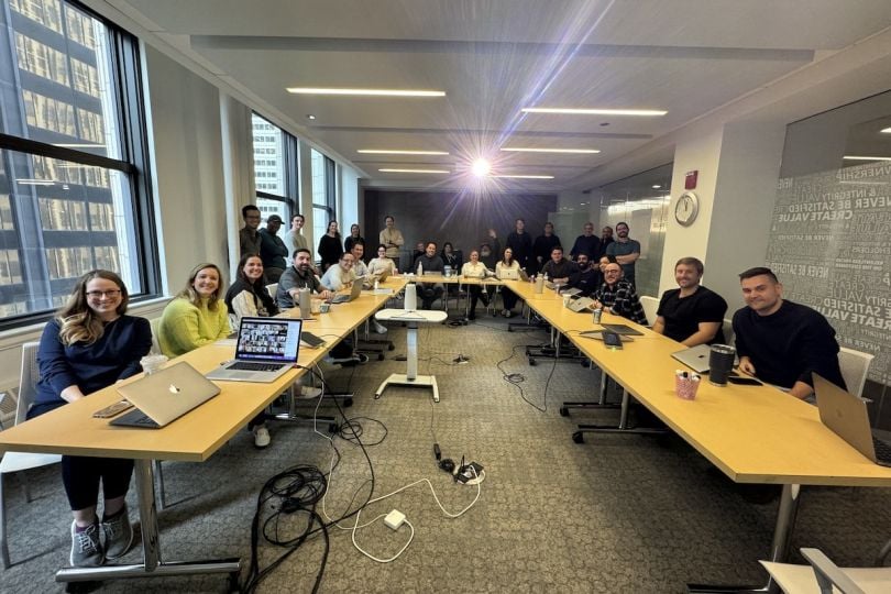 Vibes team members smile for a photo while sitting around a large conference table.