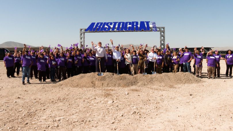 Breaking ground photo of large Aristocrat team waving 