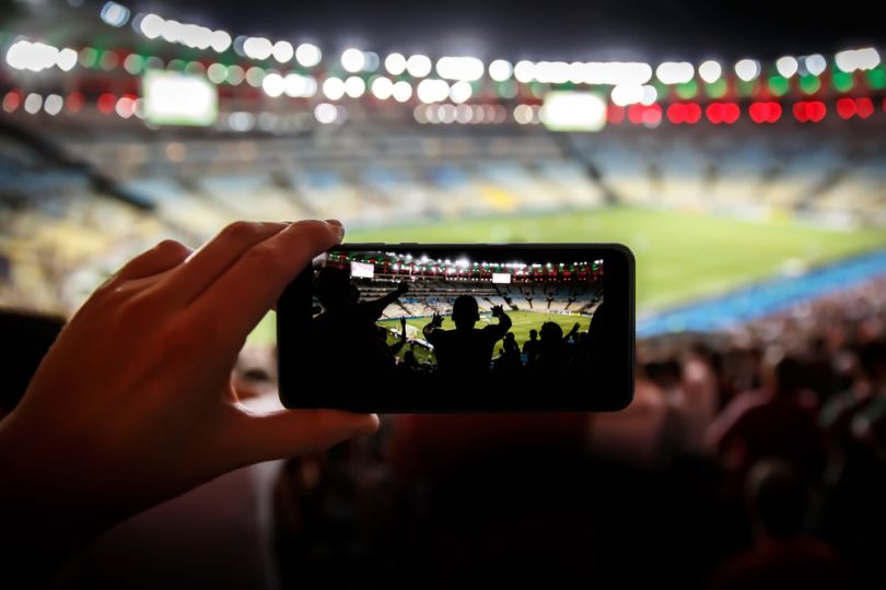 An influencer takes photos at a sporting event.