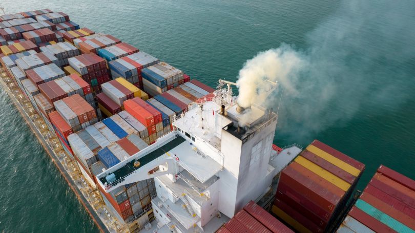 Gas emissions are depicted coming from a cargo ship.