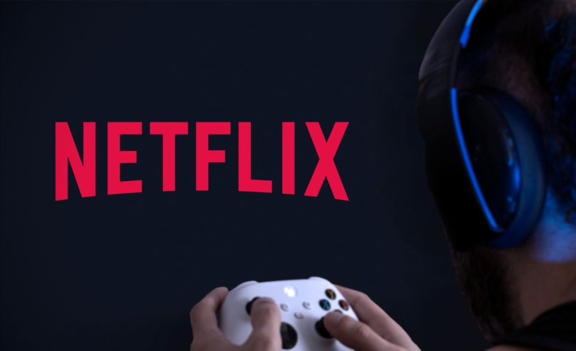 A person holding a gaming controller with the Netflix logo on the TV.