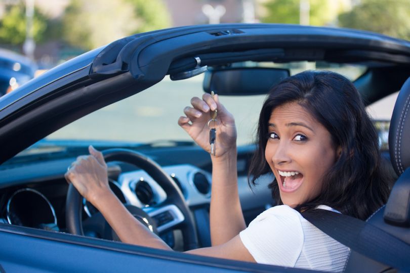 Woman in car smiling and holding keys - Cars.com