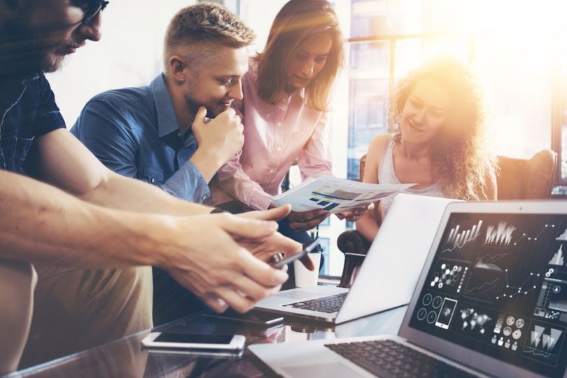 Co-workers working at a desk in a crowd