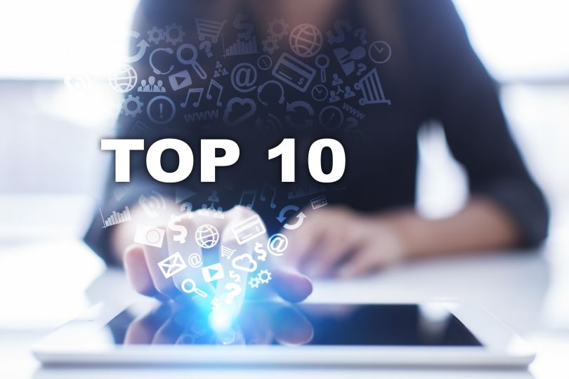 A woman from the neck down, sitting at a table. She has her finger on a tablet, and various widgets and symbols are emerging from it. TOP 10 is written in the center of the image, coming out of her tablet press.