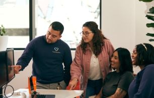 Four colleagues gather around a computer screen