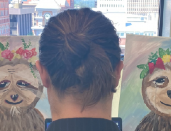 Photo of the back of Ethan Yeck's head, looking at two paintings of animal faces