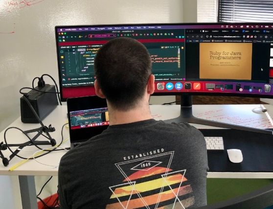 Photo of the back of Grant Callant's head, as he looks at two computer screens, one with code