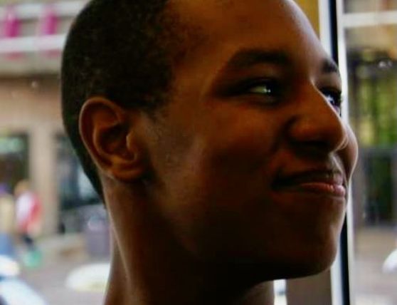 Candid headshot photo of Mikiel near a window, looking to the side